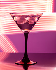 glass with cocktail and ice on a beautiful background with neon stains