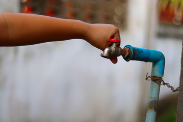 Young hand is turning off an old rusty water tap for saving water - save water concept - ecological and environmental concept