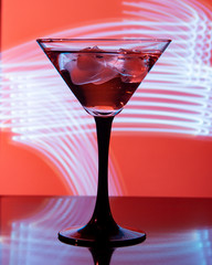 glass with cocktail and ice on a beautiful background with neon stains
