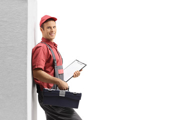 Fototapeta premium Handyman with a clipboard and a toolbox leaning against wall