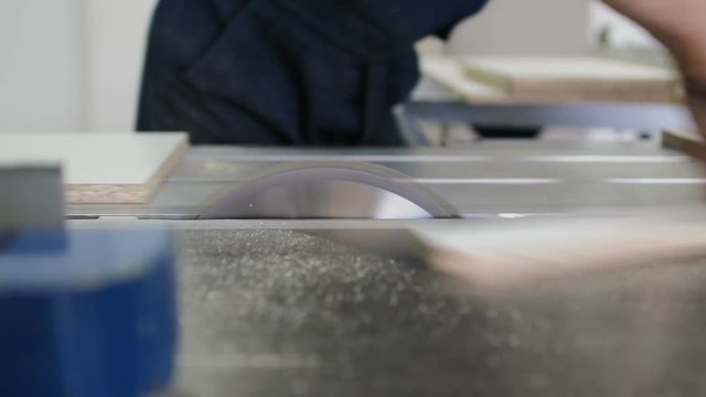 Circular saw sawing wood flying chips. Woodworking workshop.