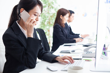 スマートフォンでクライアントに電話する女性社員