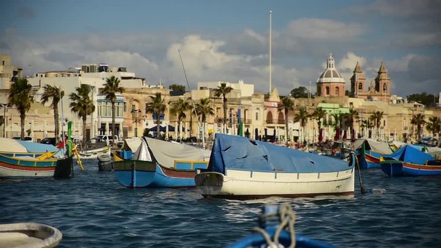 Old Colorful Boats Luzzu in Marsaxlokk harbor at sunny day. Blue sky with clouds