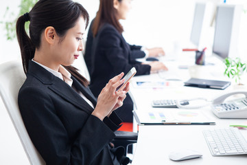 休憩中にスマートフォンを操作する女性社員