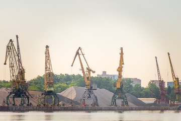 Obraz premium Port loaders and rubble heaps at sunrise