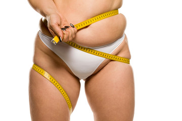 a fat woman measuring her belly on white background