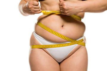 a fat woman measuring her belly on white background