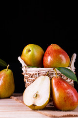 fresh pears with leaves in a basket on wooden table