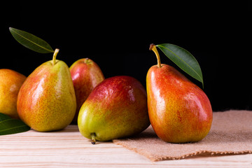 fresh pears with leaves in a basket on wooden table