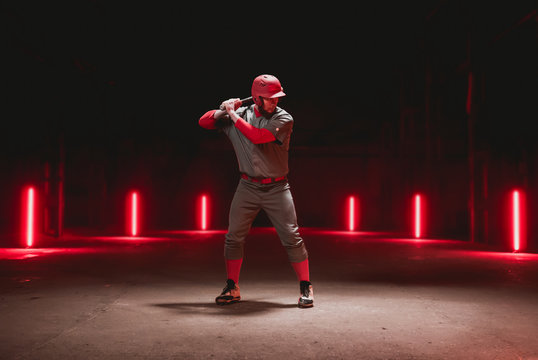 Caucasian professional baseball player batter posing against dark background in a large abandoned warehouse. 4K UHD 60 FPS SLOW MOTION