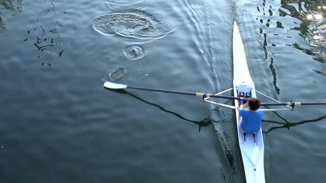 Rowers training on a competition rowing boat in a water canal. View from above.