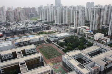 Tianjin, China - 08. September 2011: Top view of a neighbourhood with numerous apartment towers and a school sports area during a morning line up of hundreds of children