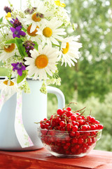 A bouquet of wildflowers and a glass bowl of red currant