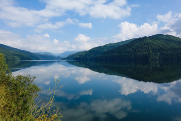 Naklejka na ściany i meble Panorama view including reflections on a mountain lake next to the Transfagarasan Highway, Romania