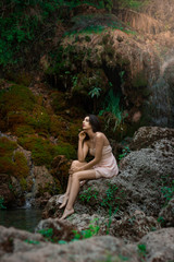 Beautiful girl posing in river. Fairytale story. Natural pool surrounded by green tree's leafs.