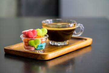 stack of macaron heart shape dessert with coffee cup on woodent plate