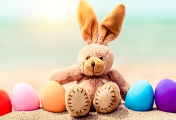 Easter bunny and color eggs on the sandy beach by the ocean