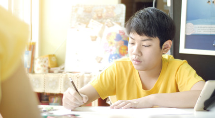 Naklejka premium Child writes homework. Children to doing home works on table in living room