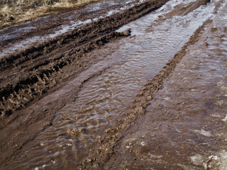 Country dirt road. Background texture of dark brown road dirt with tire tracks.