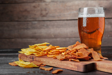 Lager beer and snacks on wooden table. Nuts, chips, pretzel