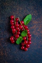 Fresh red currants in plate on dark table background.