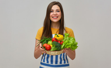 smiling woman wearing striped apron holding vegetables