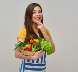 smiling woman wearing striped apron holding vegetables