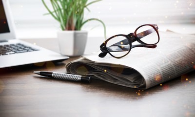 Newspaper with computer on table.