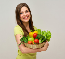 woman holding fresh vegetables and smiles with teeth.