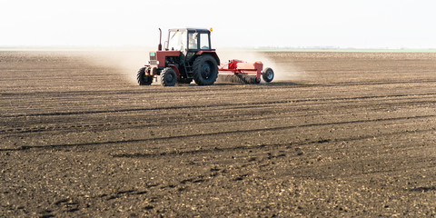 Obraz premium Farmer with tractor seeding sowing crops at agricultural field