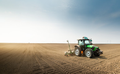  Farmer with tractor seeding sowing crops at agricultural field