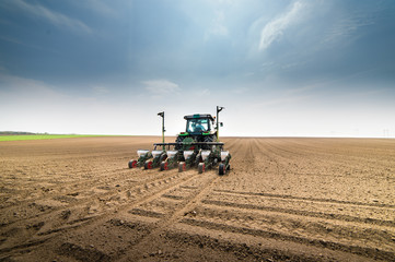 Fototapeta premium Farmer with tractor seeding sowing crops at agricultural field