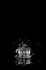 Glass of drinking water. From a glass of water splashes with reflection on a dark background.