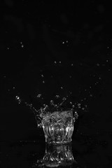 Glass of drinking water. From a glass of water splashes with reflection on a dark background.
