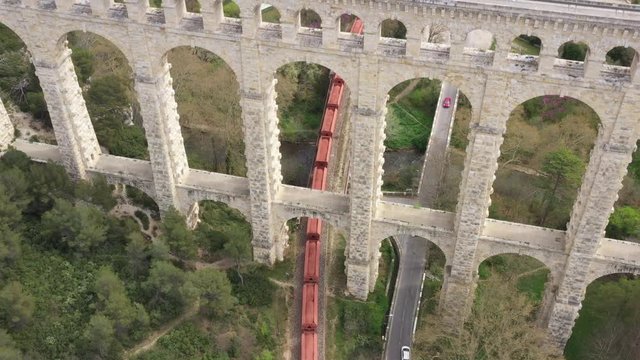 Cargo train passing under the bridge aqueduct de roquefavour France aerial view 