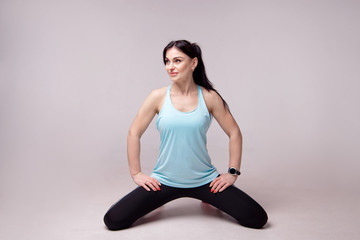 Fototapeta premium Portrait of a sporty young fitness woman doing workouts isolated on gray background