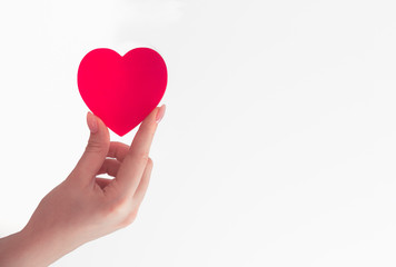 female hand holds red heart in fingers, red big paper heart, give love, white background, place for text