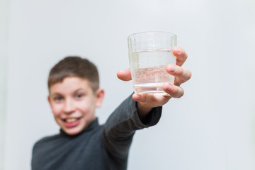 cheerful teen boy holding a glass of water