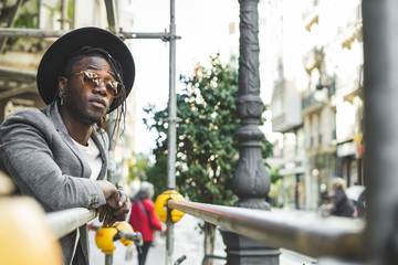 African American man portrait with sunglasses and modern hat in the street