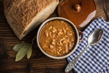 tripe stew sauce in brown ceramic pot on a wood table 