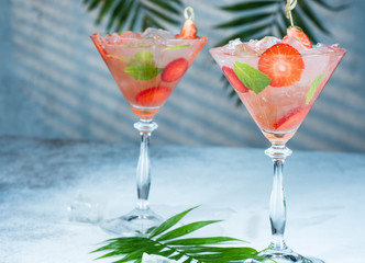 Strawberry lemonade or alcoholic cocktail with ice syrup soda and mint leaves on bar table.