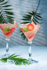 Strawberry lemonade or alcoholic cocktail with ice syrup soda and mint leaves on bar table.