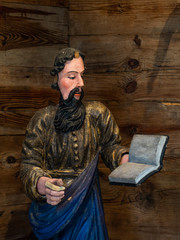 Ancient Religious Statue of Bearded Man or a saint Reading a Book against a wooden background