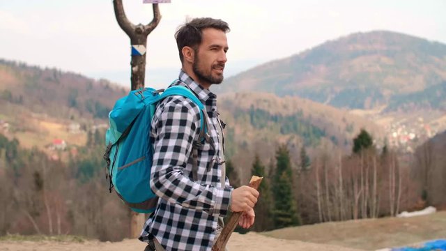 Man with backpack and stick hiking in the forest