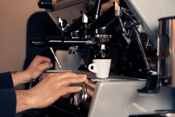 Waiter making coffee, with coffee machine and white demitasse