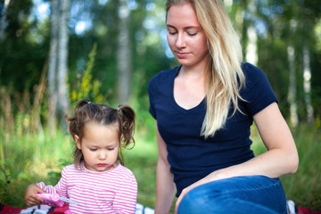 Mother and little daughter blowing soap bubbles in park. Happy and carefree childhood. Good family relations.