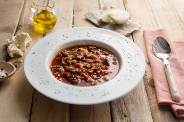 Tomato soup with beef. Oil and onion. Wooden table. Homemade. Lunch. Dinner. Kitchen.