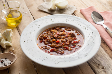 Tomato soup with beef. Oil and onion. Wooden table. Homemade. Lunch. Dinner. Kitchen.