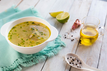 Homemade soup with chicken. Paleo diet. Wooden white table. Lime. Oil. Salt. Ingredients. 
