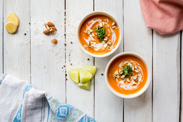 Cream soup with pumpkin, lime, ginger and nuts. Homemade. Wooden white table. Top view. Lunch....